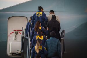 Primera expulsión extranjeros. Oficiales de PDI acompañando a abordar al avión a personas irregulares.