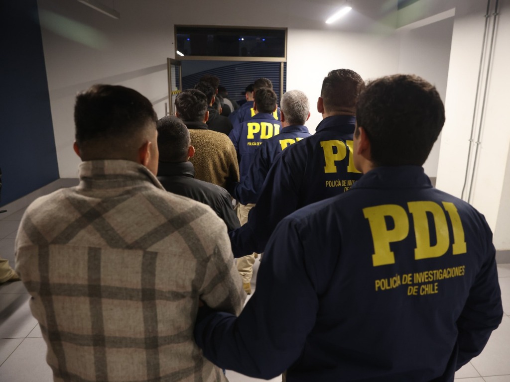 expulsados son escoltados por personal de la PDI antes de subirse al avión